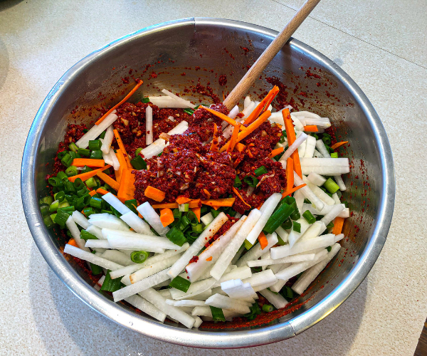 Rice flour slurry with chopped vegetables all mixed in a large metal mixing bowl