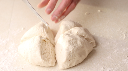 Flatbread dough being cut into 8 even slices.