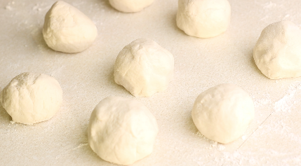Flatbread dough formed into 8 even sized balls on a counter top. 