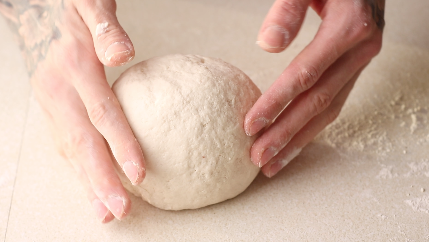Flatbread dough being shaped into a uniform ball.