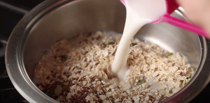 Almond milk being poured into rolled oats.