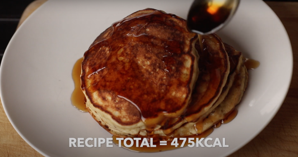 A stack of the protein pancakes with maple syrup being poured over them with text that reads 'recipe total = 475kcal'