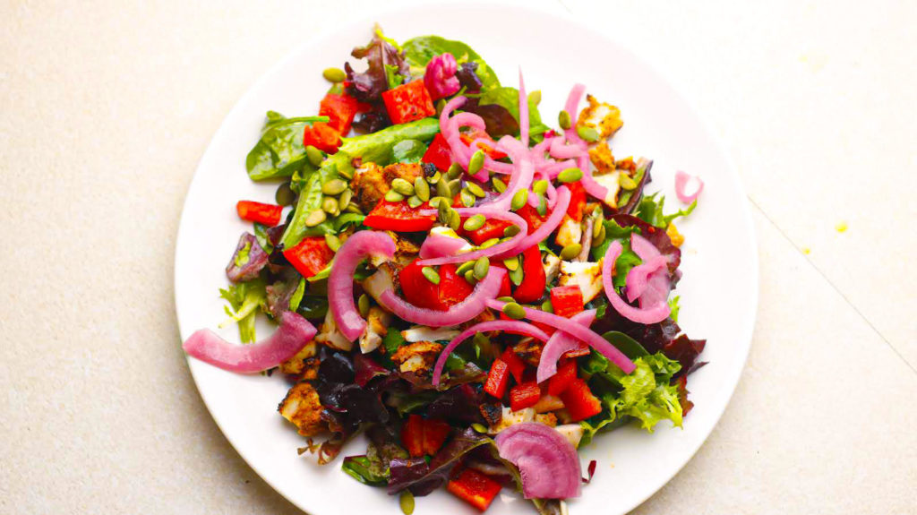 A picture of a big salad with lots of bulk to help you stick to your diet. Pickled Red Onion, Korean Style Chicken, Red Bell Peppers, and Pumpkin Seeds all served over a bed of lettuce.