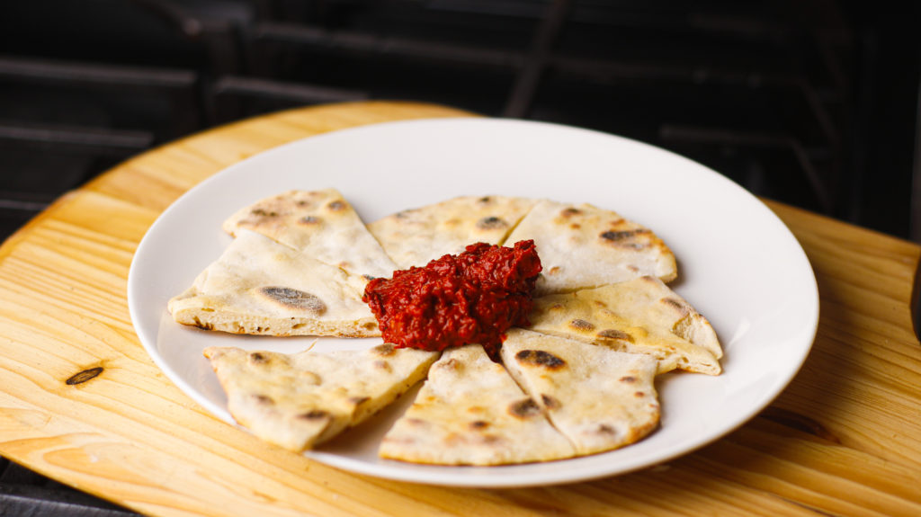 A plate of the finished healthy low calorie flatbread and a big scoop of harissa sauce. 