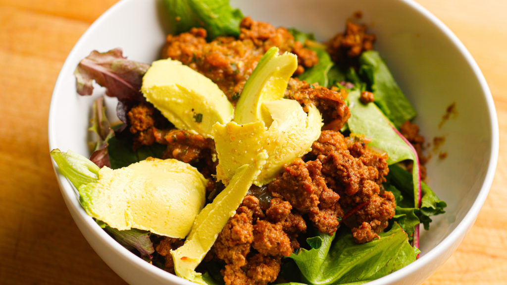 A quick 15 minute healthy mexican bowl for weight loss with a layer of rice, lettuce, beef all topped with avocado