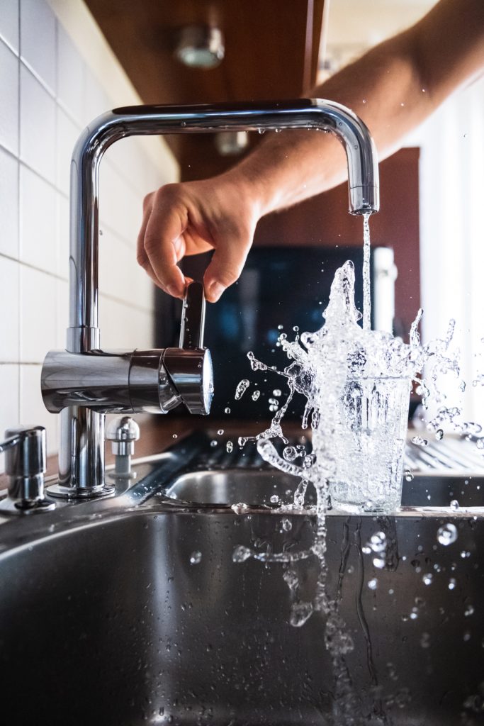 A picture of water running into a glass from a faucet. 