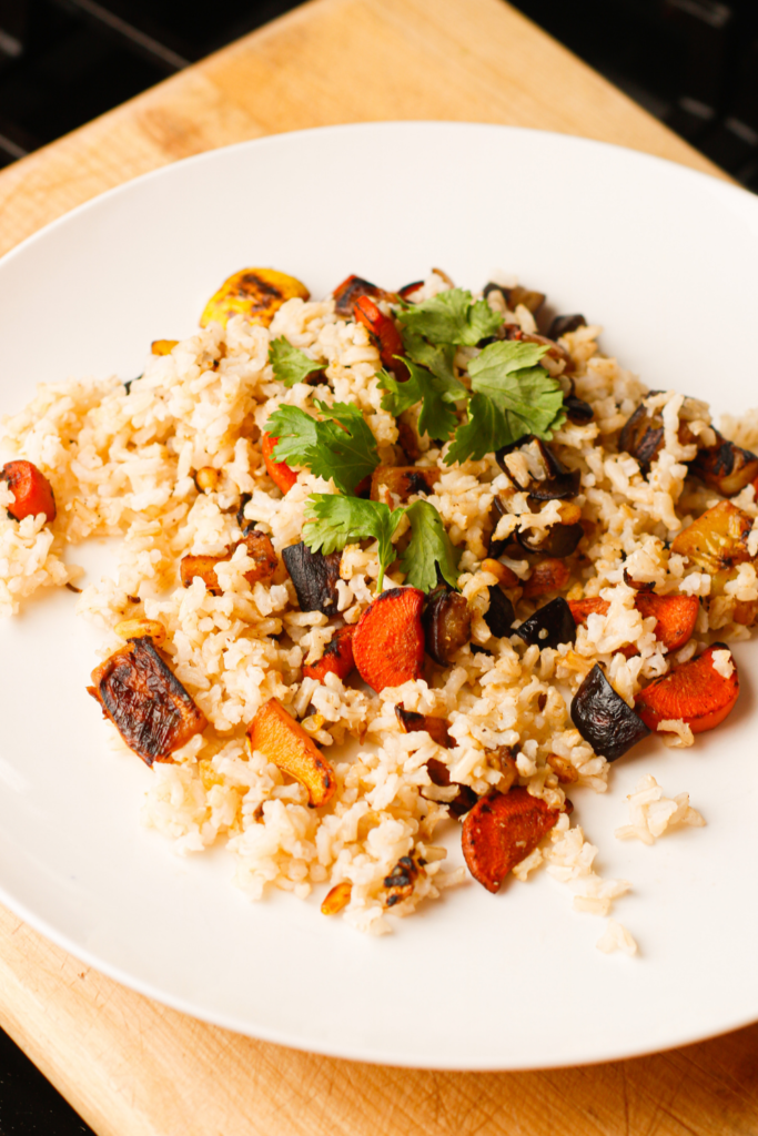 A flavor packed side of brown rice for preventing hunger when dieting. It has eggplant, summer squash, onion, carrot, cumin seeds, fenugreek seeds, and a garnish of cilantro.