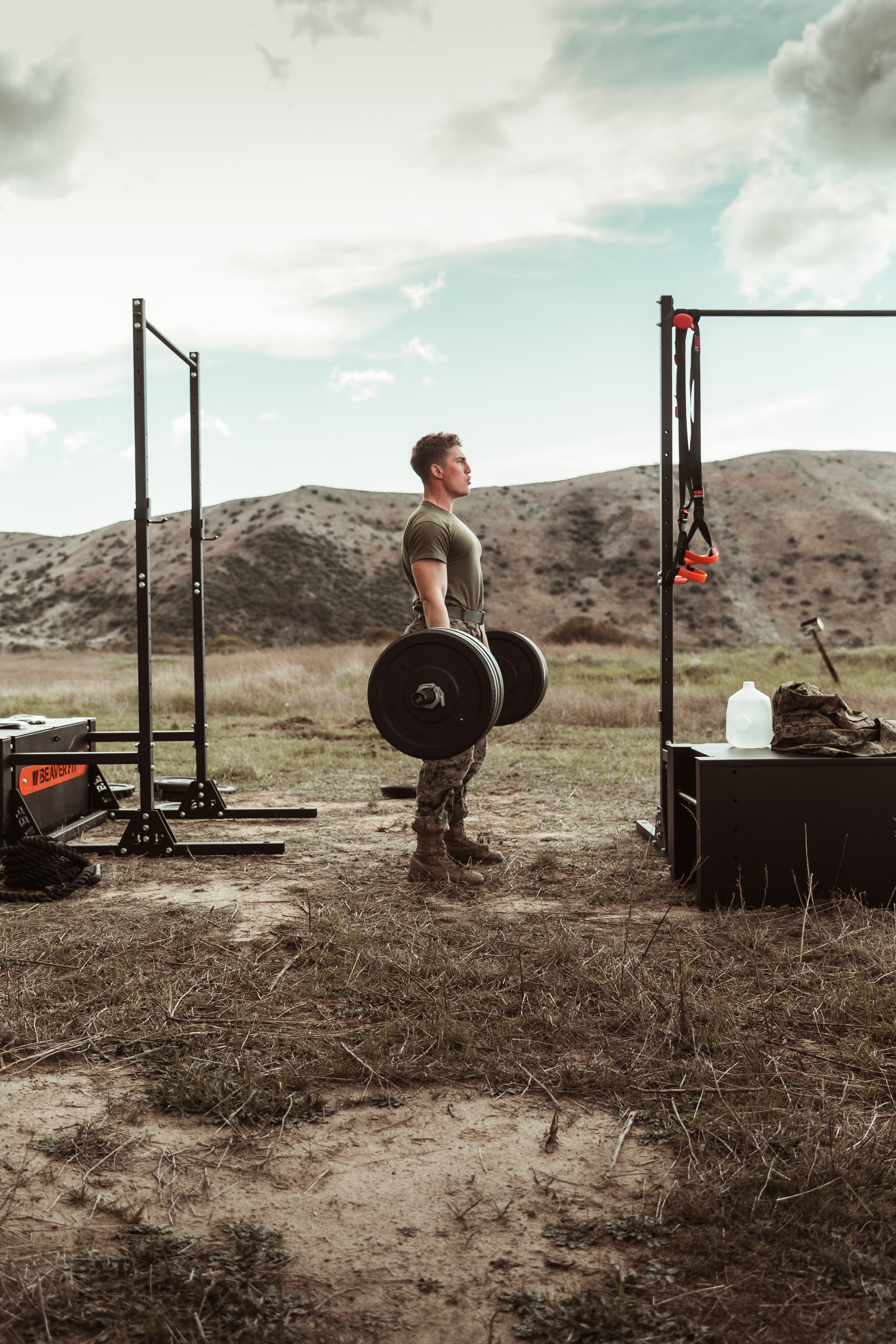 A guy performing the single best anti aging exercise, the deadlift. He is outside holding a barbell with weights loaded onto the bar.