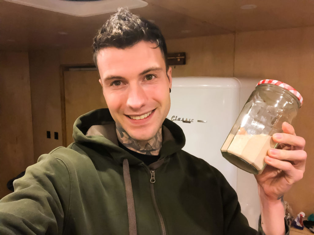 Jakob holding a jar of psyllium husk powder smiling.