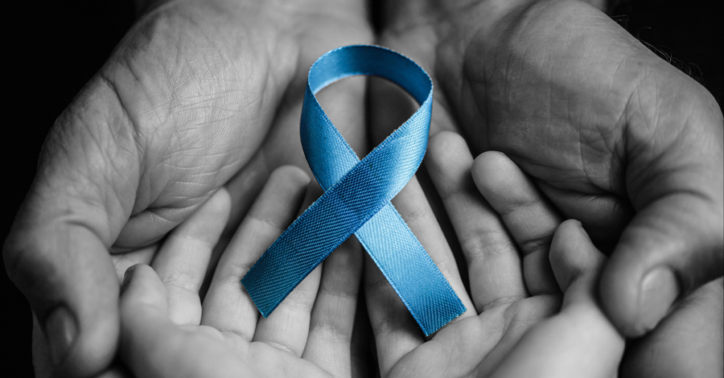 Two hands holding a blue cancer awareness ribbon. 