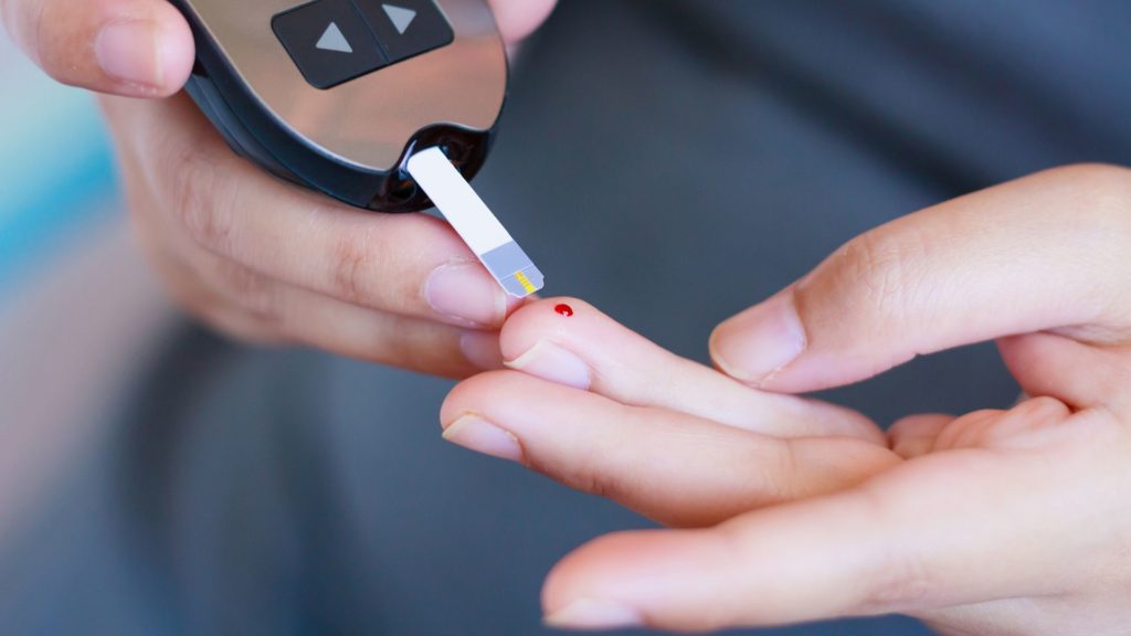 A person pricking their finger to check their glucose level. 