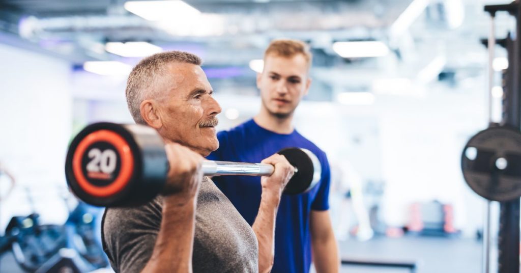 A personal trainer working with a middle-aged man.