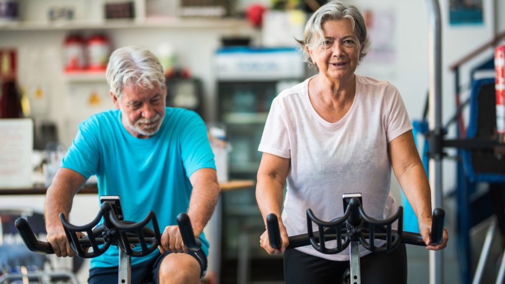 A woman and man on exercise bikes.