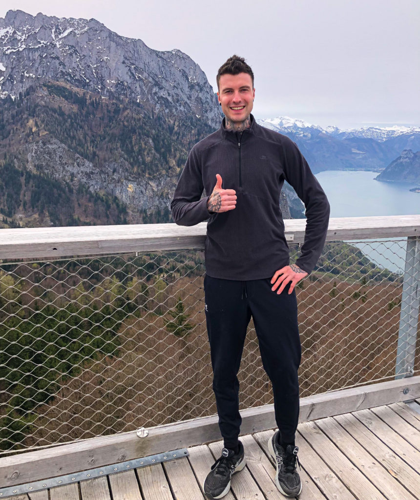 Personal Trainer Jakob Roze posing with his thumbs up in front of the Grunberg mountain in Austria.