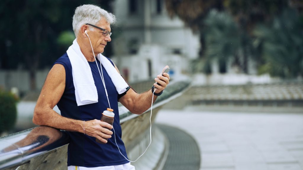 A middle-aged man wearing athletic clothing looking down at his phone.